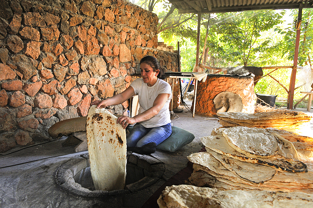 Woman making lavash (thin unleavened flatbread) made in a tandoor, called tonir in Armenian, in a restaurant beside the Noravank Monastery, near Yeghegnadzor, Armenia, Eurasia