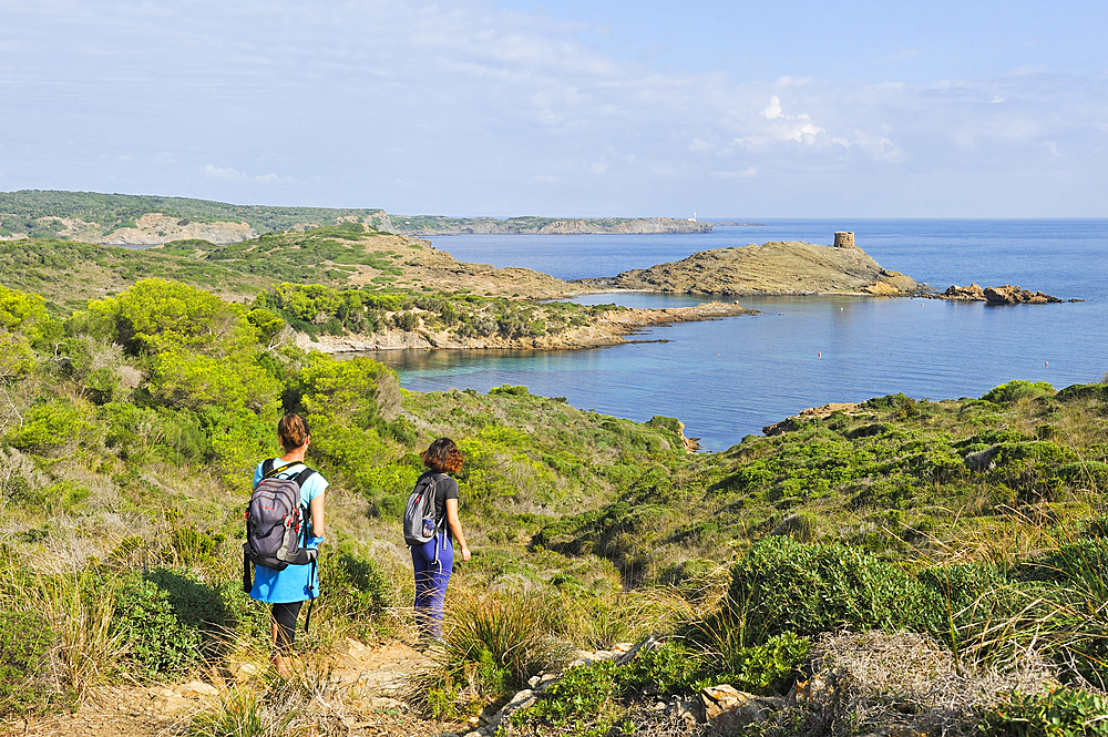 Hikers on the Cami de Cavalls, hiking trail GR 223, with the headland and watchtower Es Colomar in the background, s'Albufera des Grau Natural Park, Menorca, Balearic Islands, Spain, Mediterranean, Europe