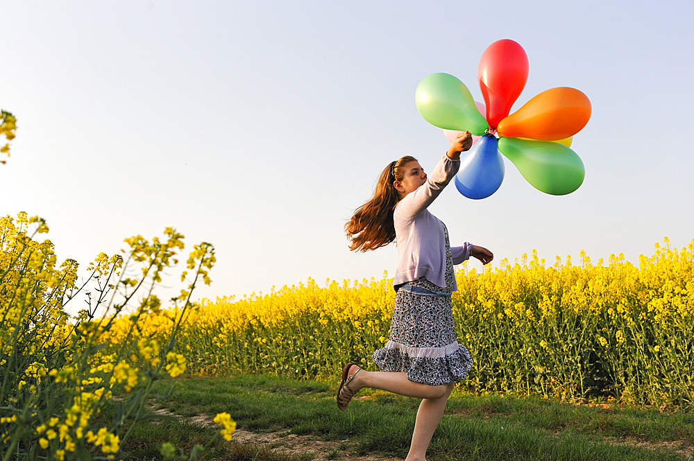 Little girl playing with balloons in the fields, Eure-et-Loir department, Centre region, France, Europe