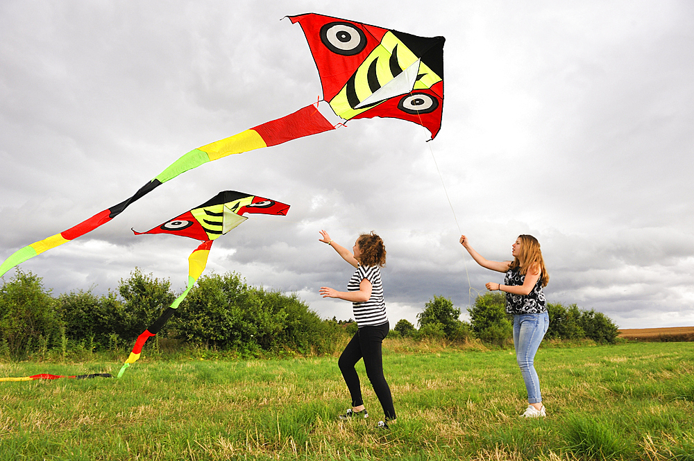 Two teenage girls flying a kite, Centre-Val de Loire region, France, Europe