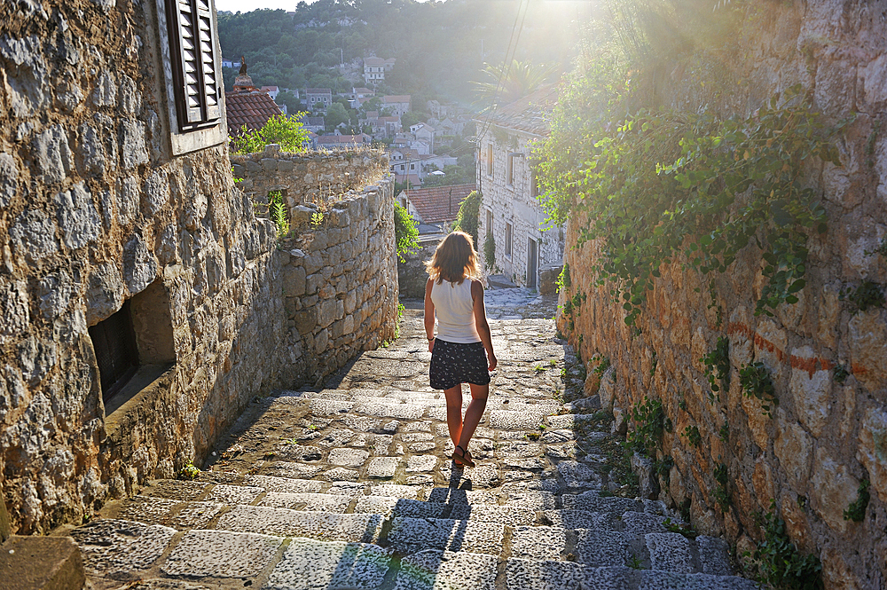 Woman walking down cobbled steps, Lastovo town, Lastovo island, Croatia, Southeast Europe