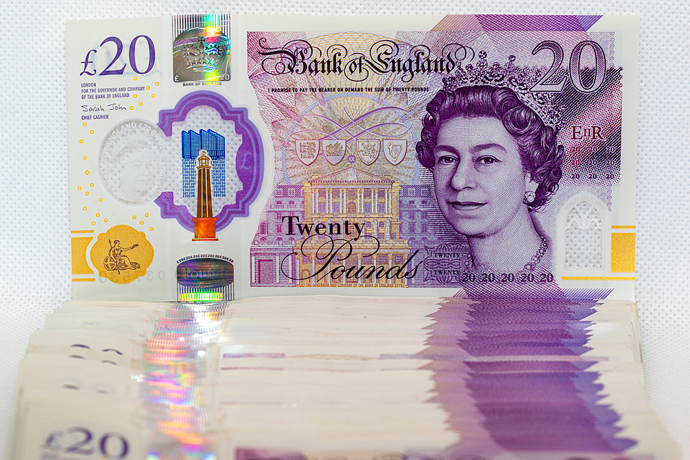 A stack of twenty pound banknotes from the Bank of England featuring Queen Elizabeth II. The banknotes are arranged vertically, with the top bill fully visible. The image is taken against a white back