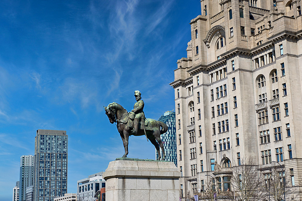 Equestrian statue of King Edward VII in Liverpool, set against a bright blue sky and featuring the Liver Building in the background.