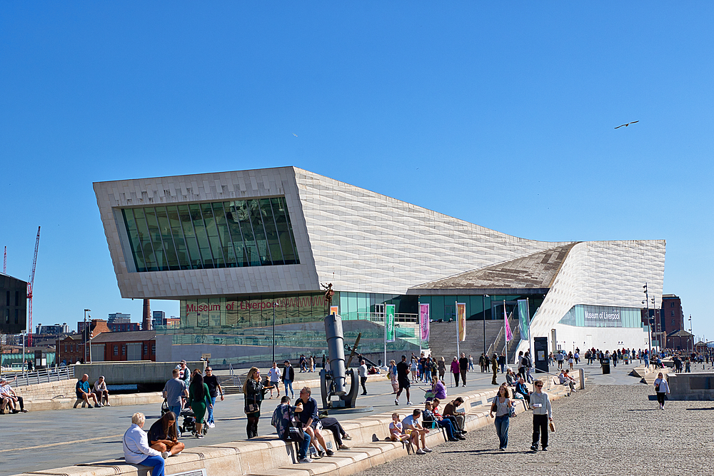 Wide shot: Museum of Liverpool with people on the plaza under a clear blue sky