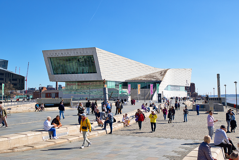 View of Museum of Liverpool with many people walking & sitting. Bright day with clear blue sky. Waterfront scene in Liverpool, UK.
