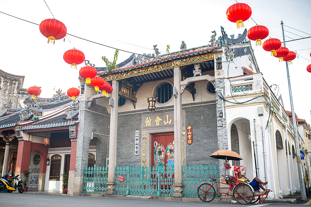 A trishaw driver resting on the side of the street of George Town, Penang, Malaysia, Southeast Asia, Asia