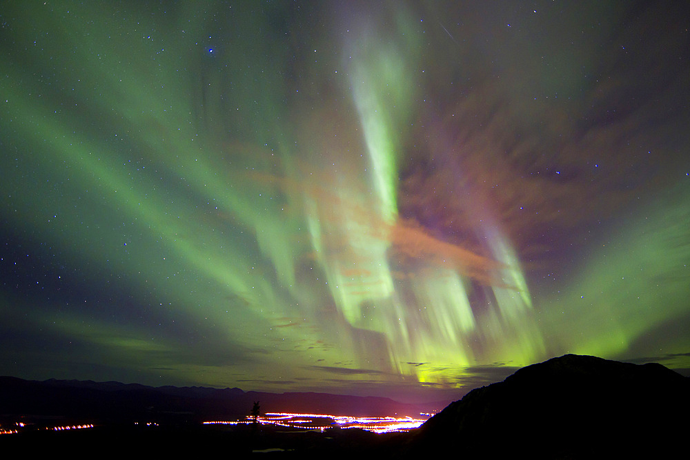 Aurora borealis over the city of Whitehorse, with Gray Mountain and shooting star, Whitehorse, Yukon, Canada.