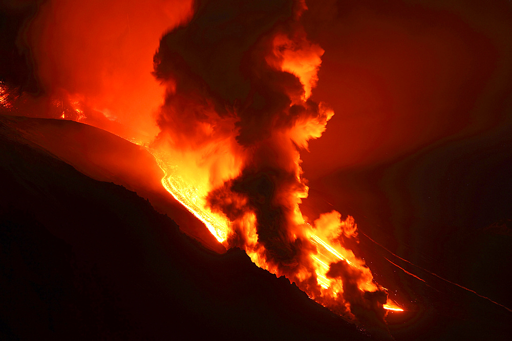 April 1, 2012 - Nighttime paroxysmal eruption at Mount Etna Volcano, Italy. Steam cloud rising as lava melts snow in Valle del Bove.