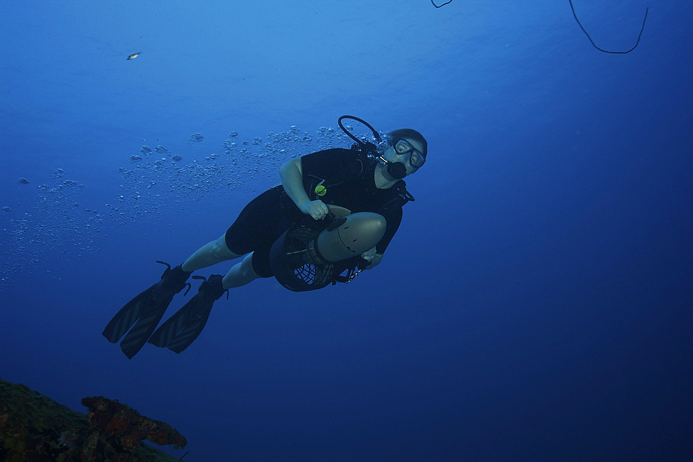 Scuba diver uses a diver propulsion vehicle to navigate the waters off the coast of Bonaire, Caribbean Netherlands.