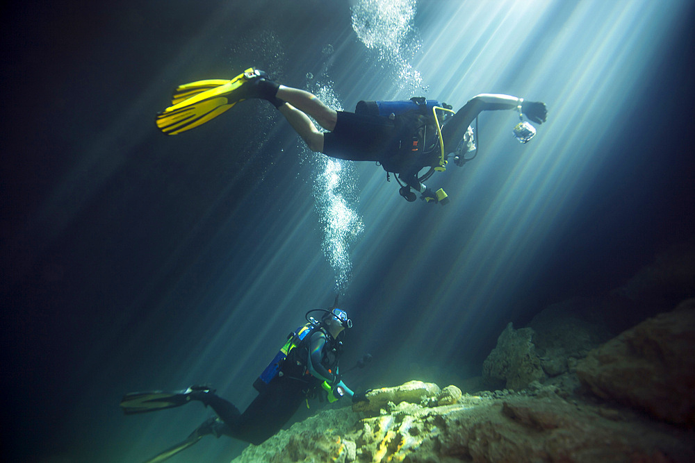 A young married couple celebrate their ten year anniversary by scuba diving in the clear freshwaters of Devil's Den Springs, a sinkhole in Williston, Florida, as the afternoon sun filters down into the cavern.