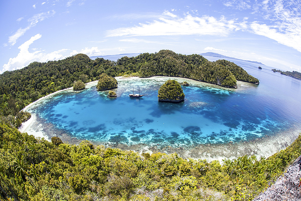 Rugged limestone islands surround a gorgeous lagoon in a remote part of Raja Ampat, Indonesia. This beautiful region is known as the heart of the Coral Triangle and is a popular destination for scuba divers and snorkelers.