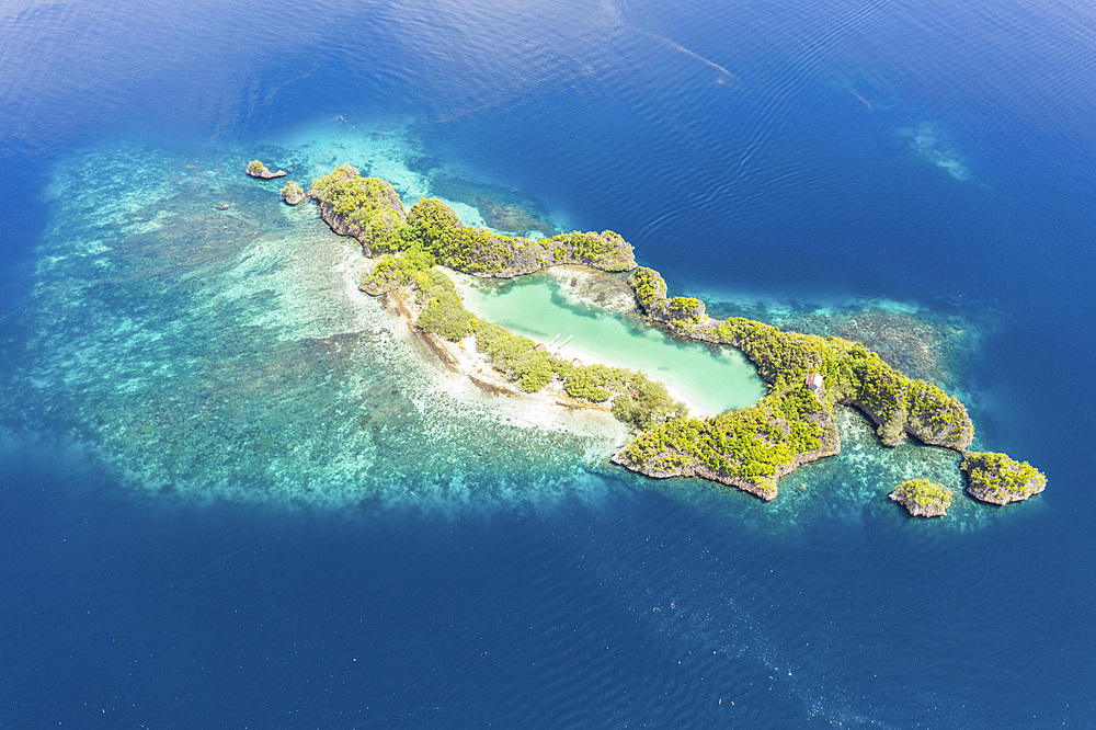 Morning light shines on a beautiful limestone island in Raja Ampat, Indonesia. This region is known as the heart of the Coral Triangle due to its incredible marine biodiversity. It is a popular destination for scuba divers and snorkelers.