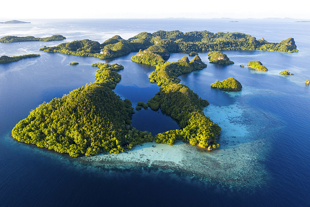 Aerial view of beautiful limestone islands scattered about the seascape in Raja Ampat, Indonesia. This tropical area is known for its extraordinary marine biodiversity and is a popular destination for divers and snorkelers.