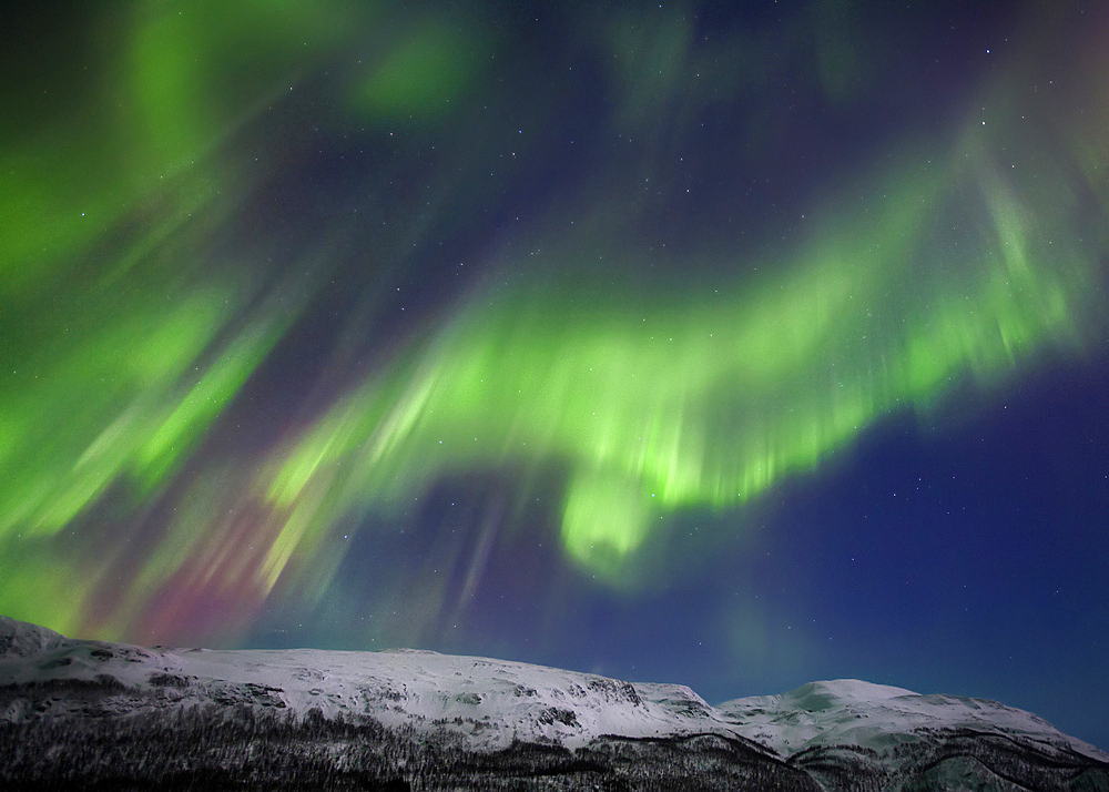 Aurora borealis over Blafjellet Mountain in Troms County, Norway. Auroras are the result of the emissions of photons in the Earth's upper atmosphere.
