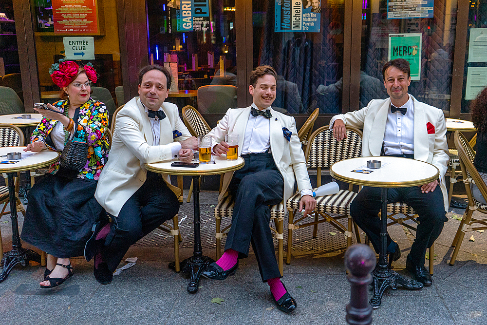 Musicians taking a break with colourful woman outside Le Duc des Lombards on summer evening
