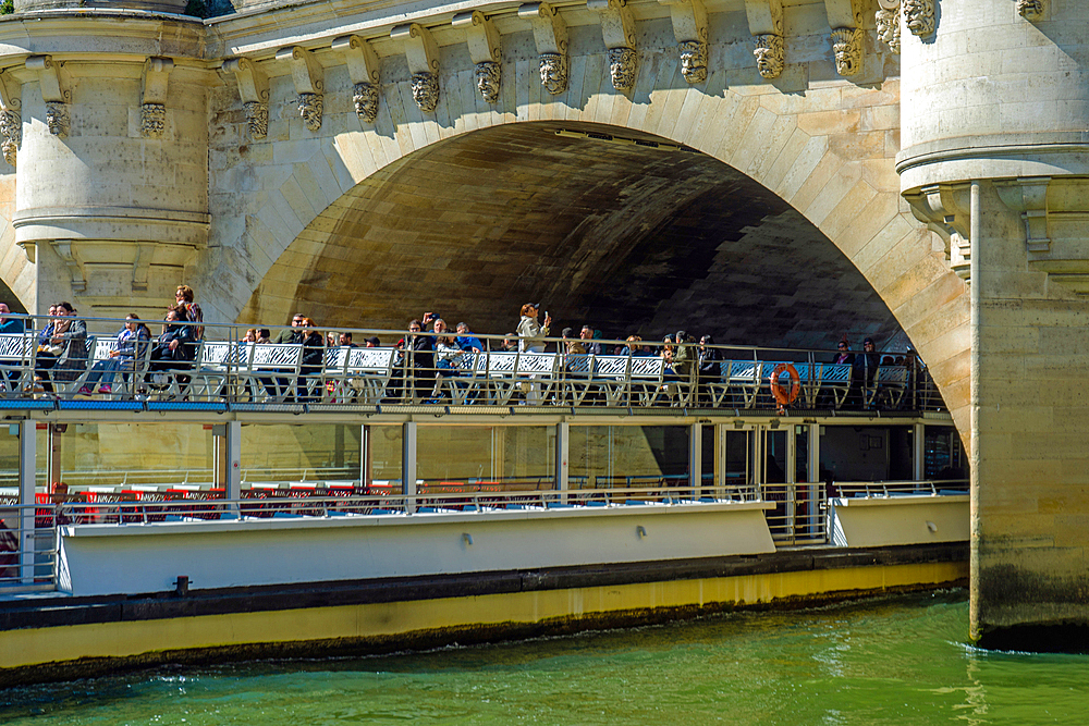 Tourist boat passing under Pont Neuf ion bright winter day