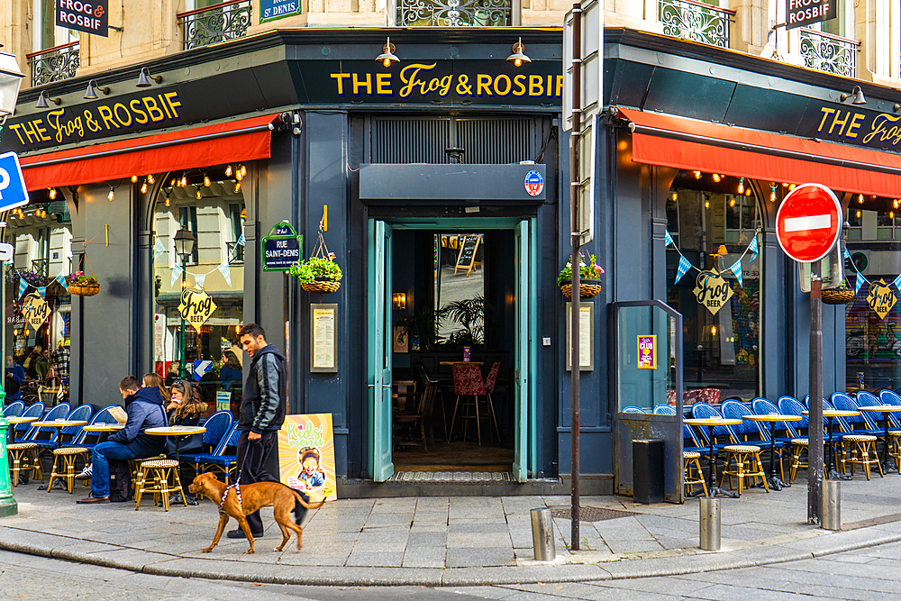 Young man with dog in front of bar The Frog and Rosbif on Rue Saint-Denis