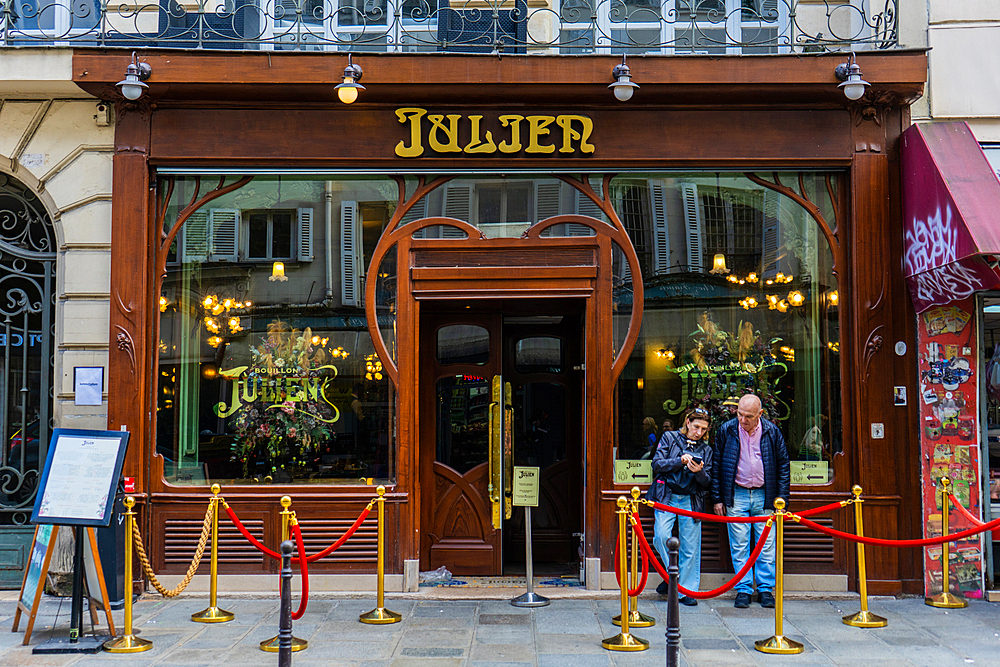 Couple outside restaurant Bouillon Julien on Rue Saint-Denis, Paris, France