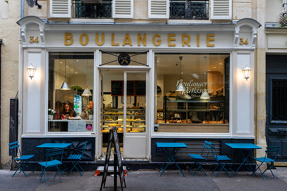 Two women drinking coffee in window of boulangerie in the Marais, Paris, France