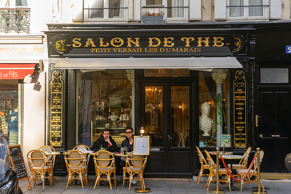 Two men on terrace of tea room Salon de The on Rue Francois Miron, Paris, France