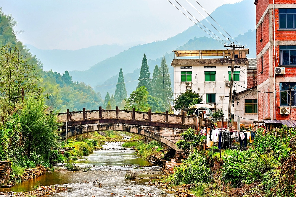 Stone bridge over a river in picturesque Guodong Ancient Village, Wuyi County, Jinhua City, Zhejiang Province, China. The 1000 year old village is still well inhabit with ancient buildings as early as the Wanli period (1573-1620) during the Ming Dynasty.