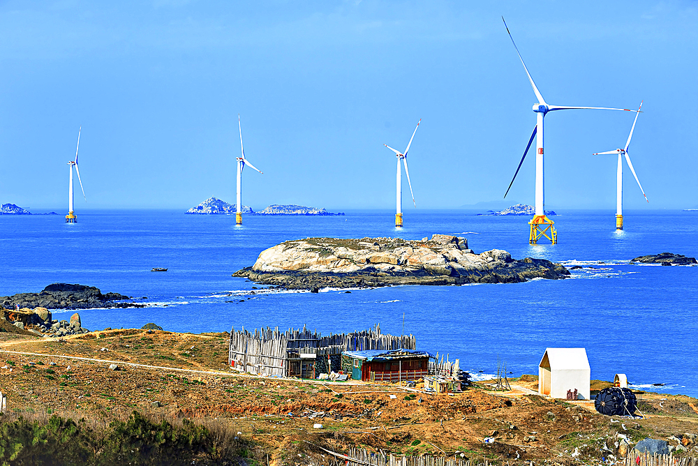 A cottage on the coast of Pingtan Island with windmills in the sea. Pingtan Island, Fuzhou City, Fujian Province, China.