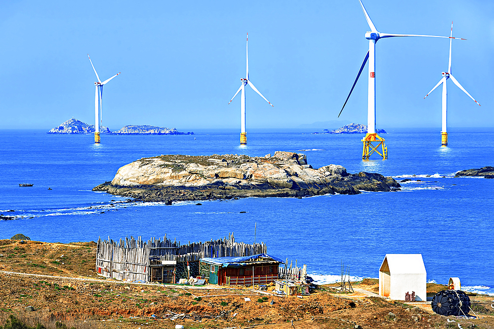 A cottage on the coast of Pingtan Island with windmills in the sea. Pingtan Island, Fuzhou City, Fujian Province, China.
