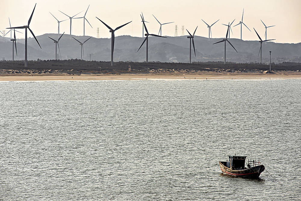 Lone fishing boat with windmills in the background. Pingtan Island, Fuzhou City, Fujian Province, China.