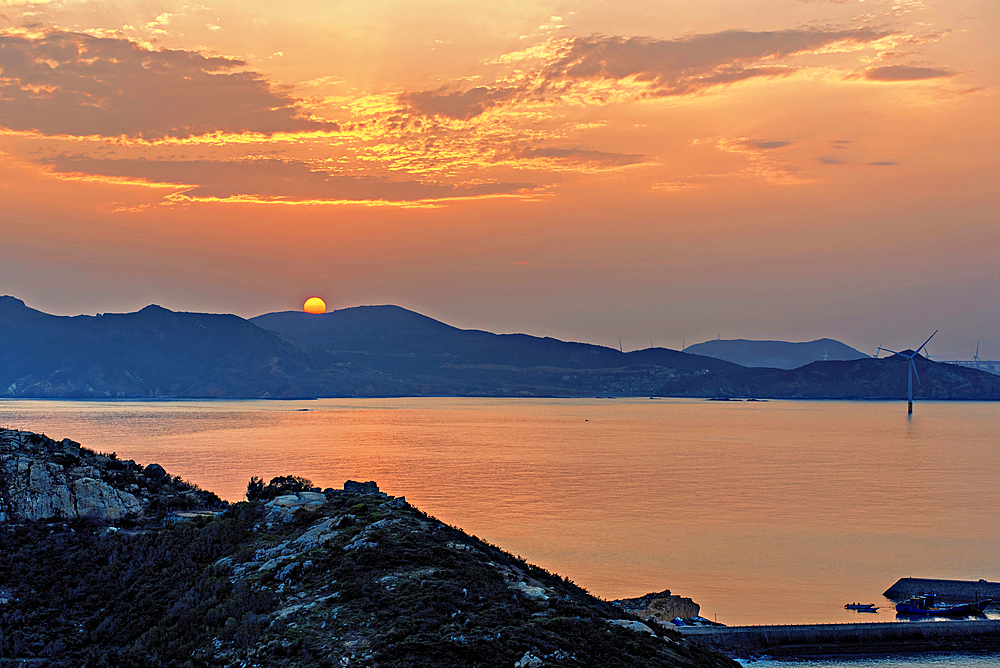 Final peek of a setting sun over the hills and the sea of Pingtan Island, Fuzhou City, Fujian Province, China.