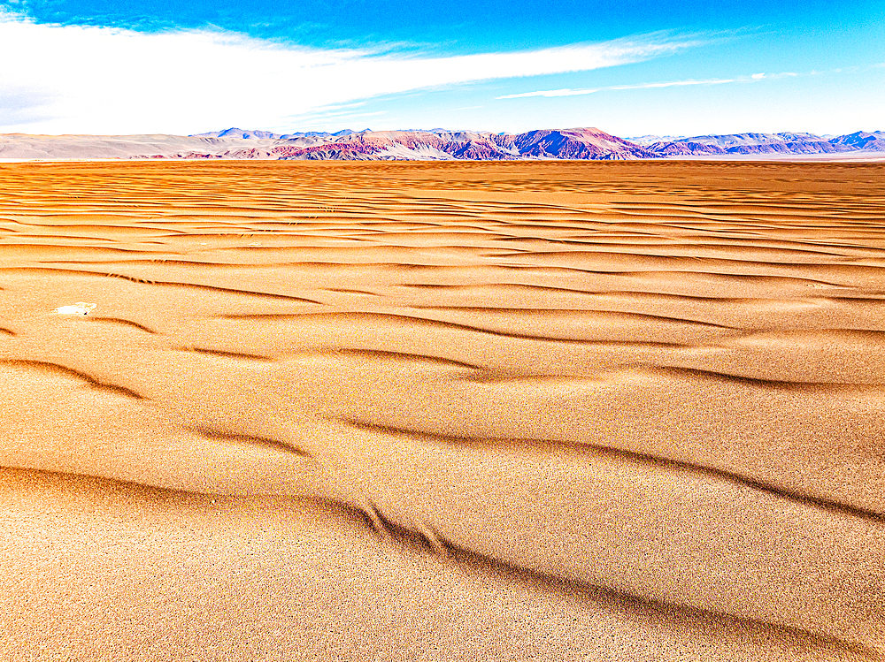 Golden sand dunes of desert with volcanoes on background, aerial view, Campo de Piedra Pomez, El Penon, Catamarca, Argentina