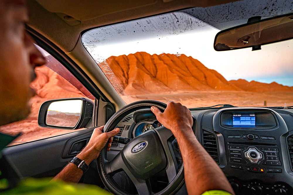 Man looking at the idyllic wild landscape from windscreen while driving an off road vehicle, Labyrinth Desert, Puna, Argentina