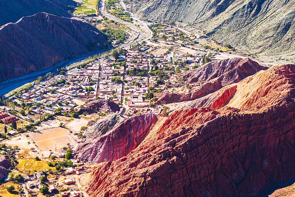 Aerial view of the ancient village of Purmamarca in a valley framed by red rocks mountains, Argentina
