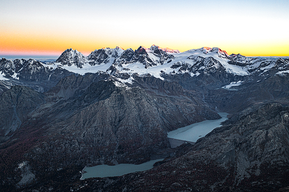 Aerial view of the snowy Bernina Range, Campo Moro dam and reservoir at sunrise in autumn, Valmalenco, Lombardy, Italy