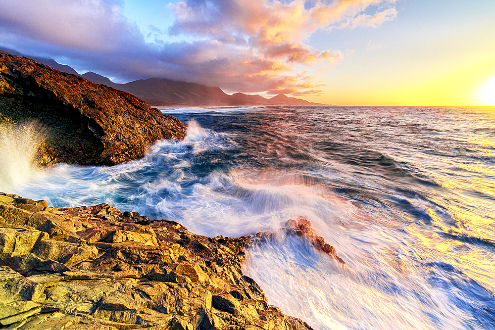 Sunset over the breaking waves washing Cofete Beach, Jandia Nature Park, Fuerteventura, Canary Islands, Spain