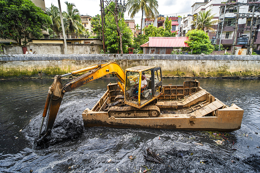 Municipality worker digging out garbage from a polluted canal using an excavator, in Guwahati, India on 27 May 2025.