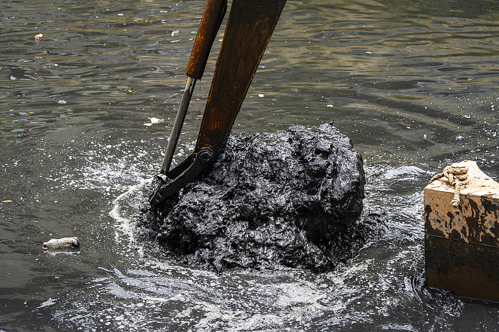 Digging out garbage from a polluted canal using an excavator