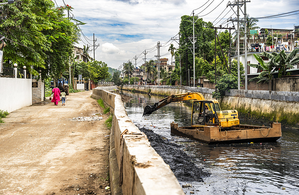 Municipality worker digging out garbage from a polluted canal using an excavator, in Guwahati, India on 27 May 2025.