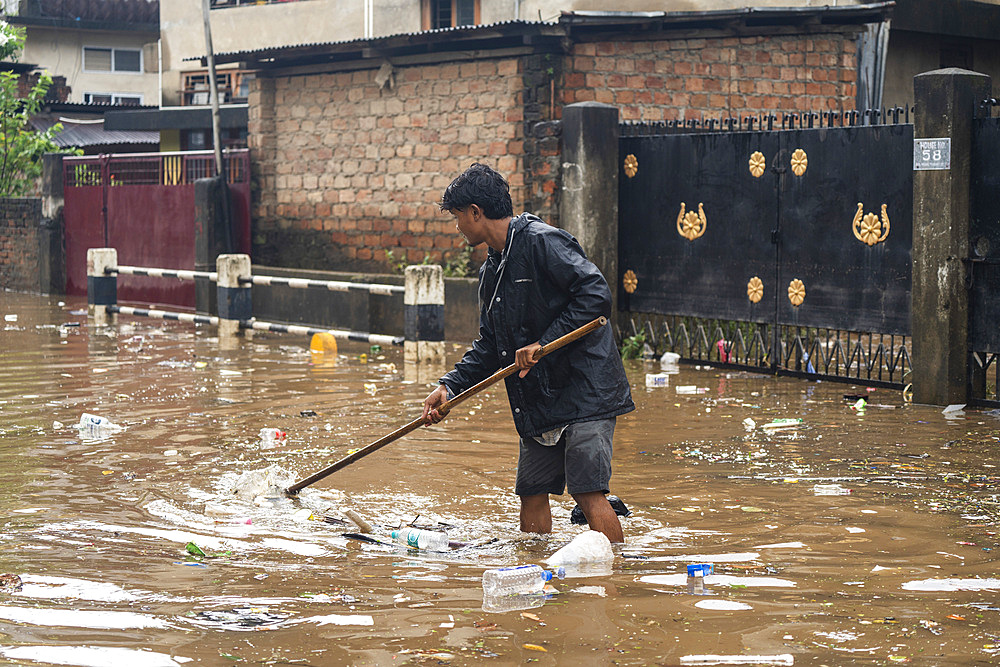 A person try to clear garbages in a flooded street after heavy monsoon rains in Guwahati, India on May 31, 2025.