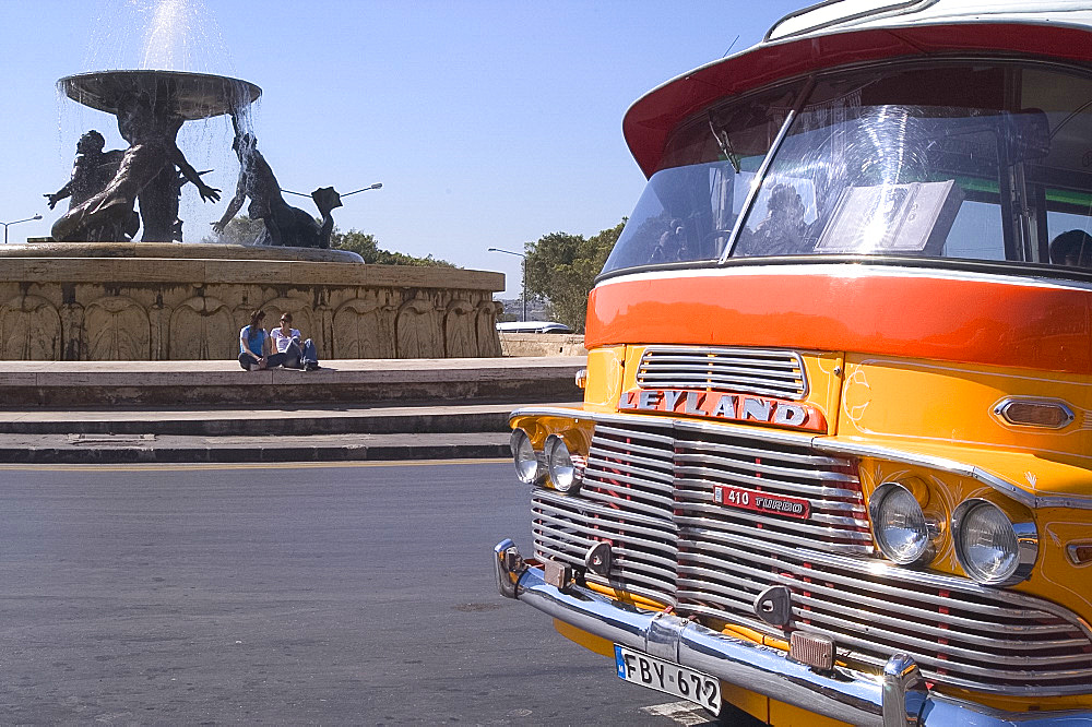 Orange bus next to a fountain in Valletta, Malta, Mediterranean, Europe