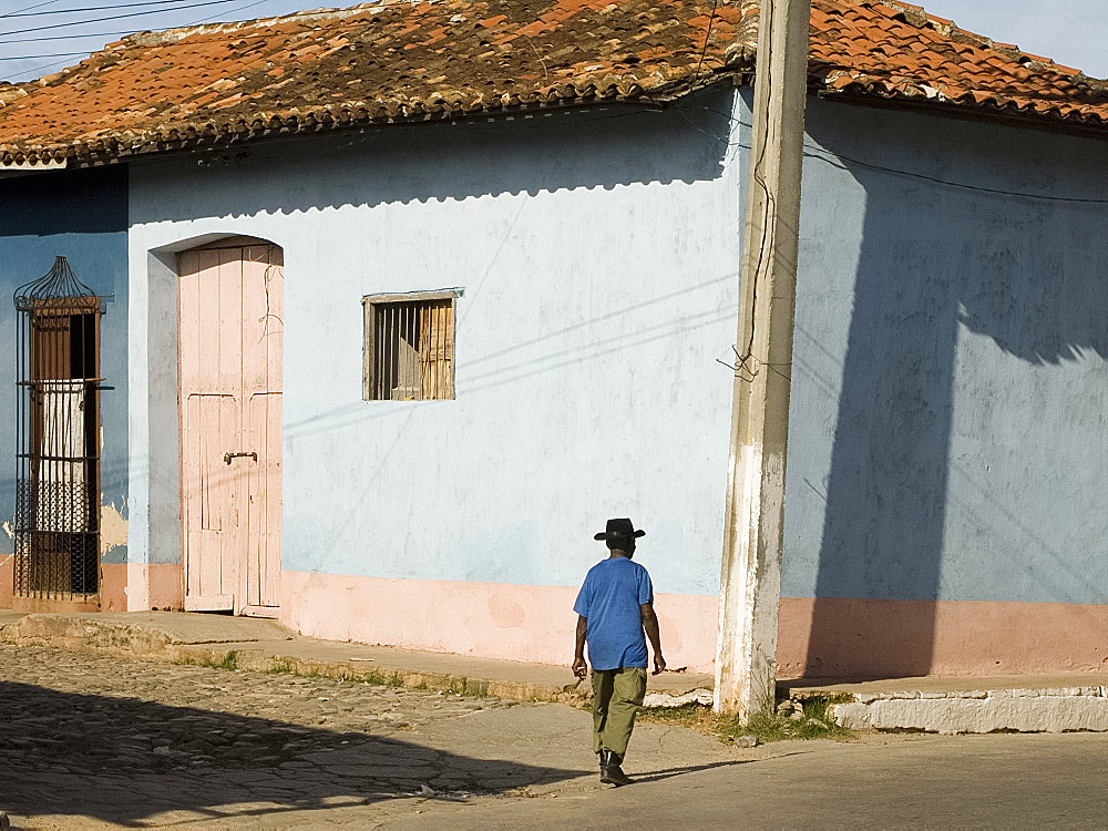 A man walking past colourfully painted houses in Trinidad, UNESCO World Heritage Site, Cuba, West Indies, Central America