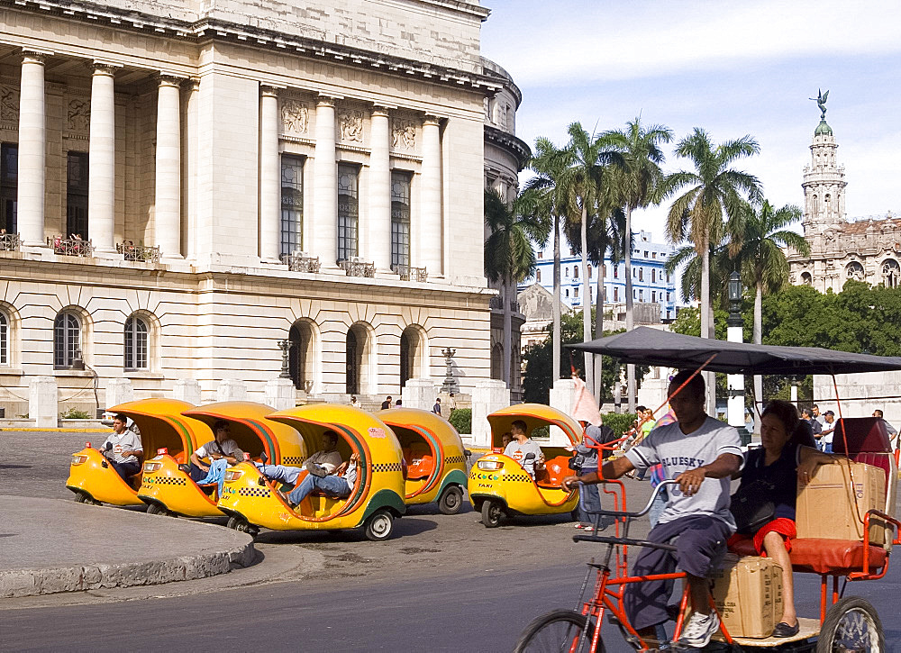 A rickshaw passing 'coco' taxis in central Havana, Cuba, West Indies, Central America