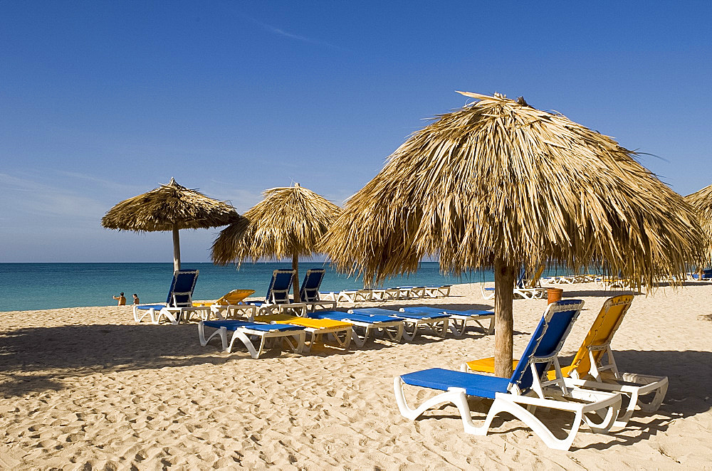 Sun beds and thatched umbrellas on the Playa Ancon next to the Hotel Brisas del Mar, Trinidad, Cuba, West Indies, Central America