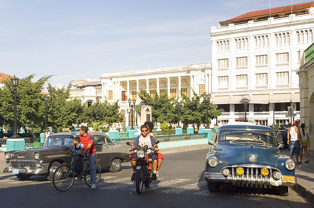 Old cars on a corner on Parque Cespedes with the Hotel Casa Granda and the Casa de la Cultura Miguel Matamoros in the background, Santiago de Cuba, Cuba, West Indies, Central America