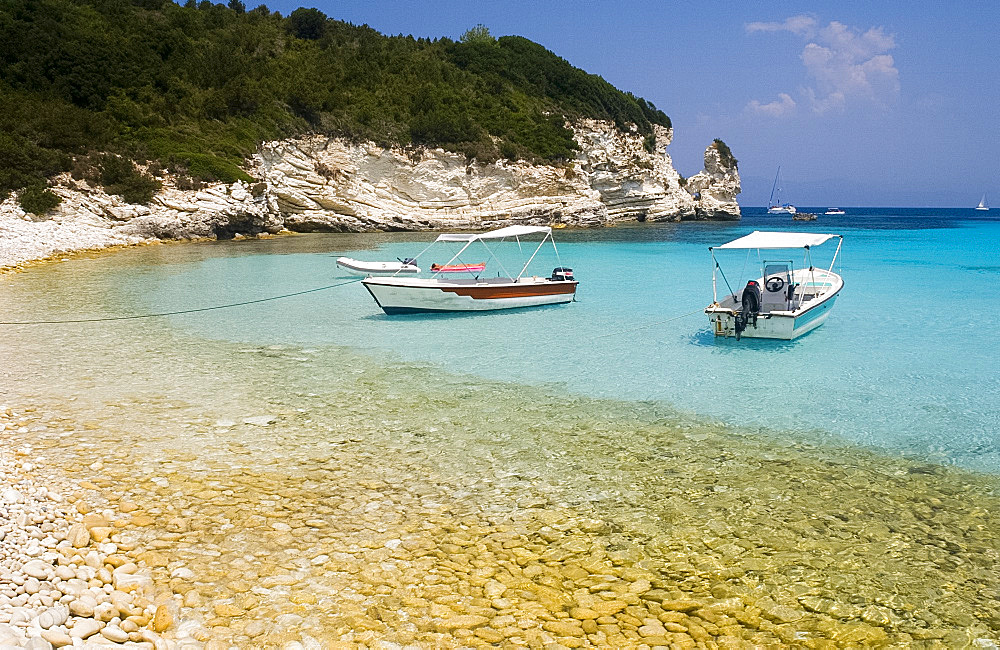 Boats and limestone cliffs at Mesovrika Beach on the northeast coast, Anti-Paxos, Ionian Islands, Greek Islands, Greece, Europe