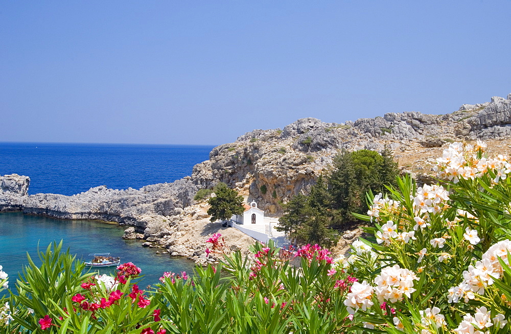 A small white church and fising boat in St. Paul's Bay near Lindos, Rhodes, Dodecanese Islands, Greek Islands, Greece, Europe