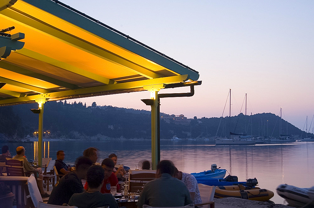 A waterside taverna at dusk in Lakka, Paxos, Ionian Islands, Greek Islands, Greece, Europe