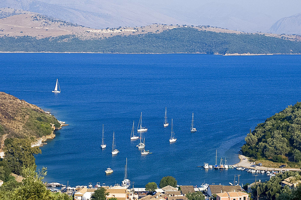 View over the harbour of Ayios Stefanos, across the Ionian Sea to the mountains of Albania, Corfu, Ionian Islands, Greek Islands, Greece, Europe