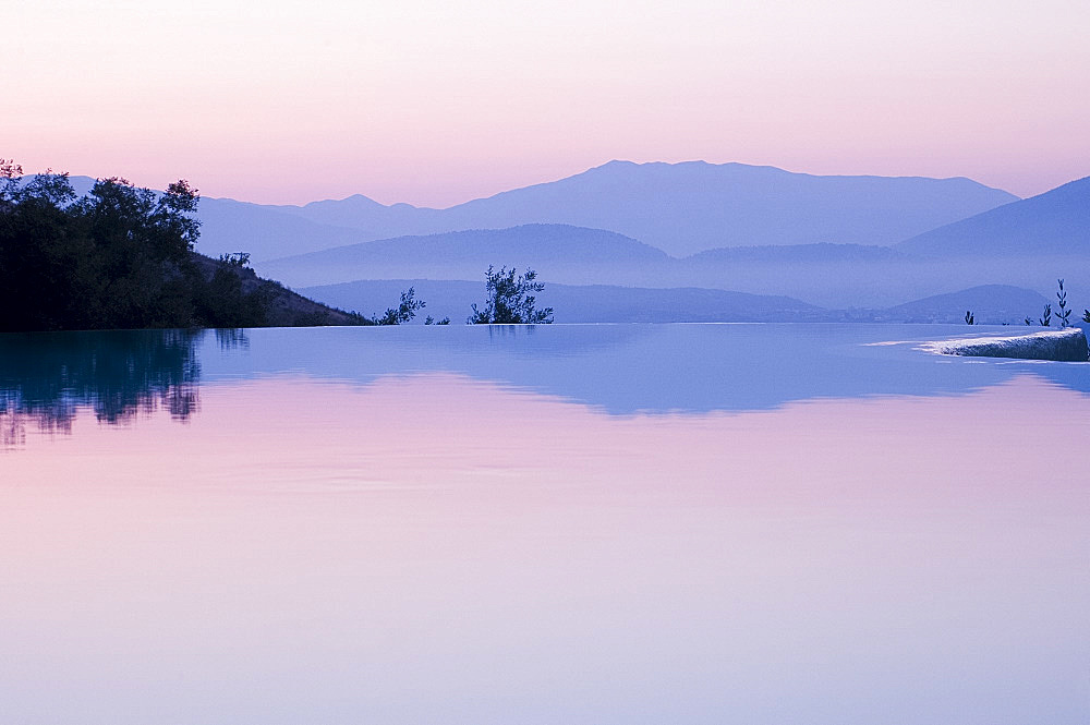 An infinity pool at sunrise and mountains of Albania taken from Ayios Stefanos, Corfu, Ionian Islands, Greek Islands, Greece, Europe