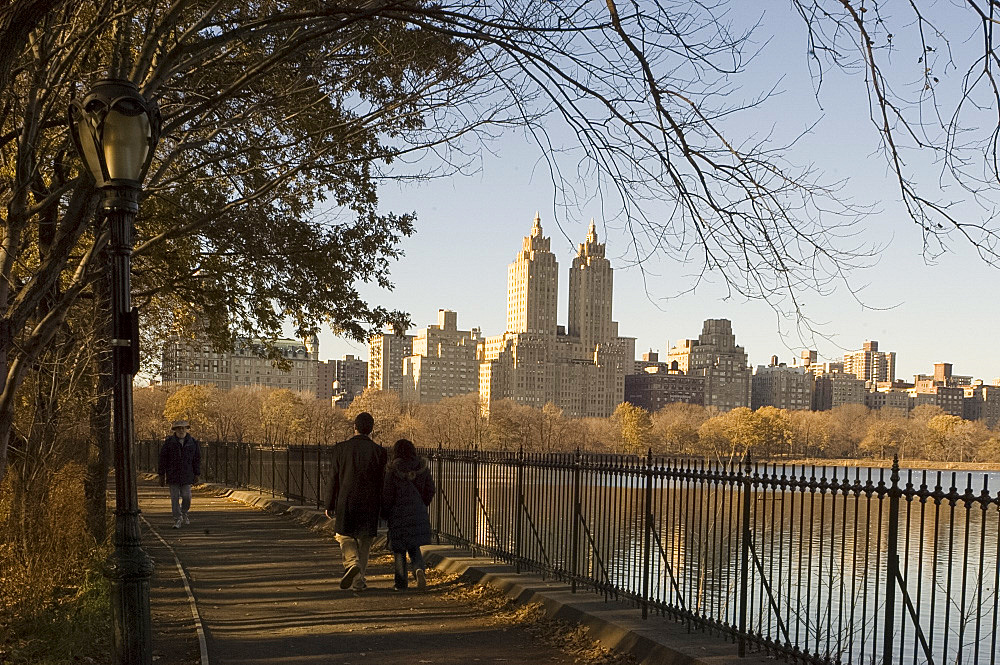 People walking next to the resevoir in Central Park in winter with tall buildings of Central Park West in the background, New York City, United States of America, North America