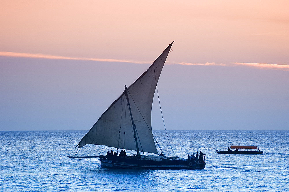 A traditional wooden dhow sailing near Stone Town at sunset, Zanzibar, Tanzania, East Africa, Africa